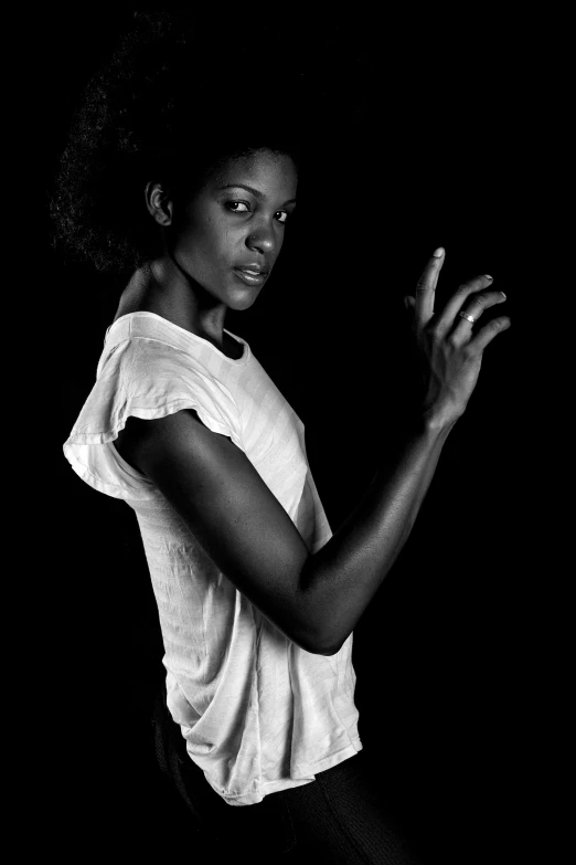 a black and white photo of a woman holding a tennis racquet, by Clifford Ross, art photography, black skin!!!, dressed in a white t shirt, gesture, mysterious woman