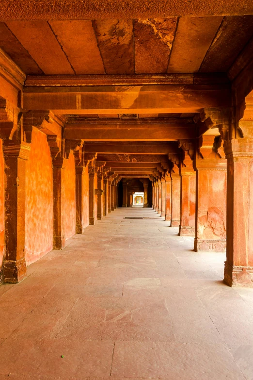 a long corridor in the middle of a building, inspired by Steve McCurry, renaissance, ancient india, parks and monuments, fan favorite, red sandstone natural sculptures