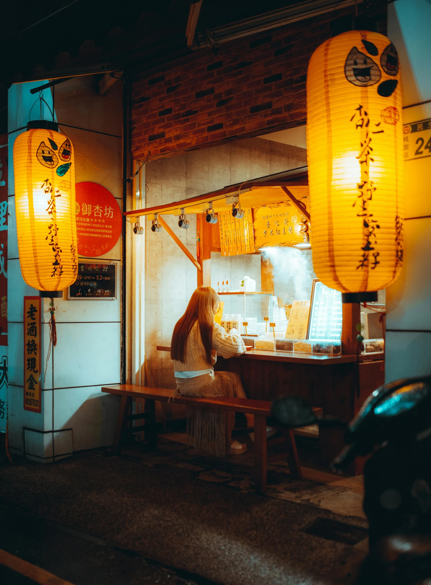 a woman is sitting outside at night looking through her window