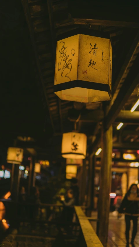 a group of people walking down a street at night, an album cover, trending on unsplash, mingei, hanging lanterns, dimly-lit cozy tavern, high resolution photo, square