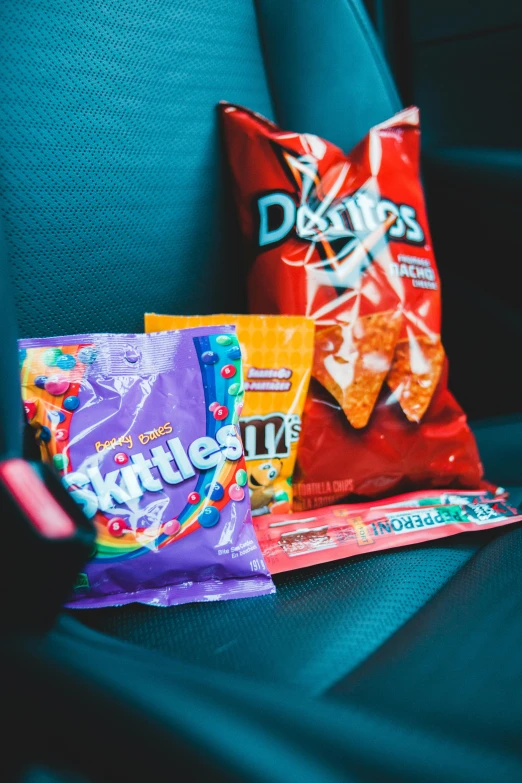 a bag of chips sitting on top of a car seat, inspired by Daniel Schultz, pexels, visual art, candies, pretty colors, inside a gas station, instagram picture