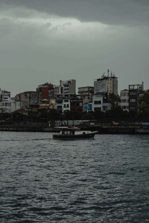 a large body of water with a boat in it, by Nabil Kanso, surrounding the city, gray skies, on a boat, waterfront houses