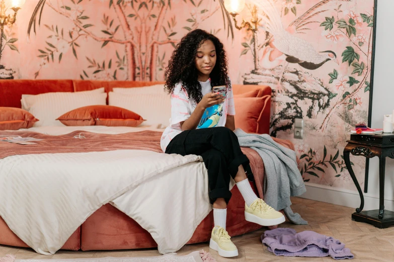 a woman sitting on the edge of a bed reading a book