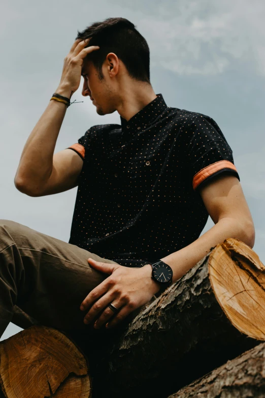 a man holding his head as he sits on a tree stump