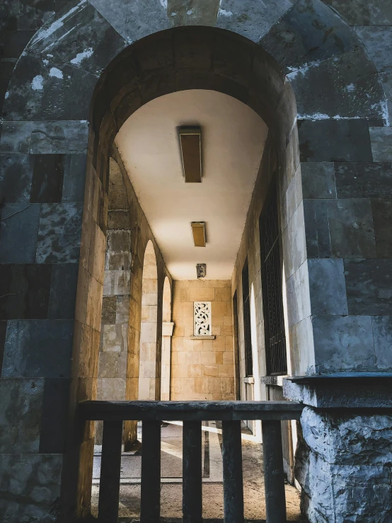 a clock that is on the side of a building, an album cover, pexels contest winner, romanesque, stone tile hallway, dappled lighting, brutalist courtyard, doorway