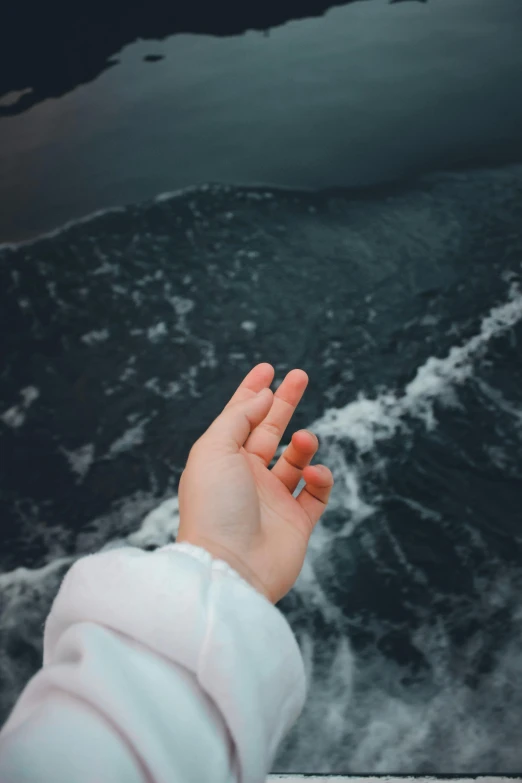 a hand reaching for soing that is in the ocean