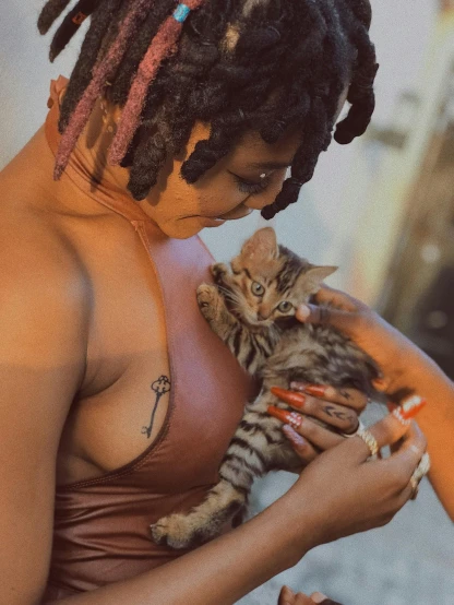 a woman holding a kitten in her arms, an album cover, trending on pexels, bralette, afropunk, body modification, high quality picture