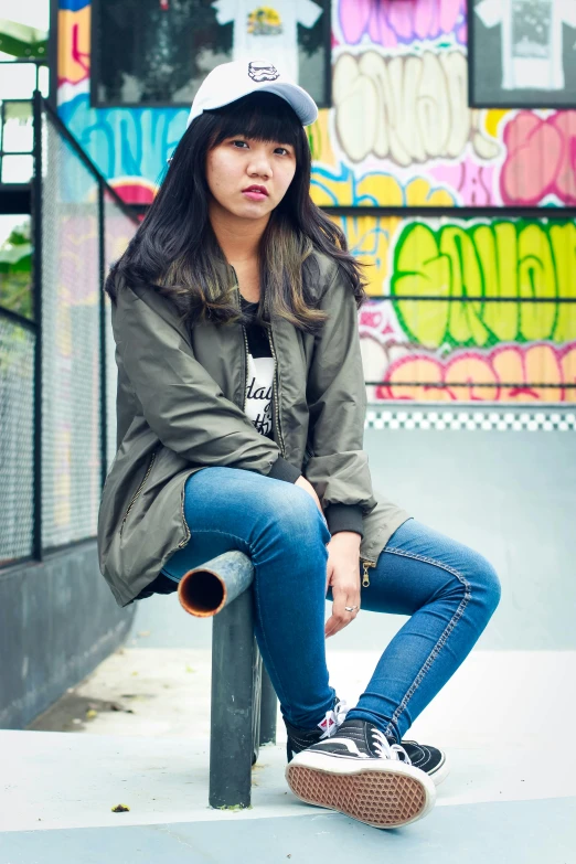 a woman sitting on the edge of a skateboard ramp, inspired by Natasha Tan, unsplash, graffiti, wearing dark green bomber jacket, ((portrait)), young asian woman, casual pose