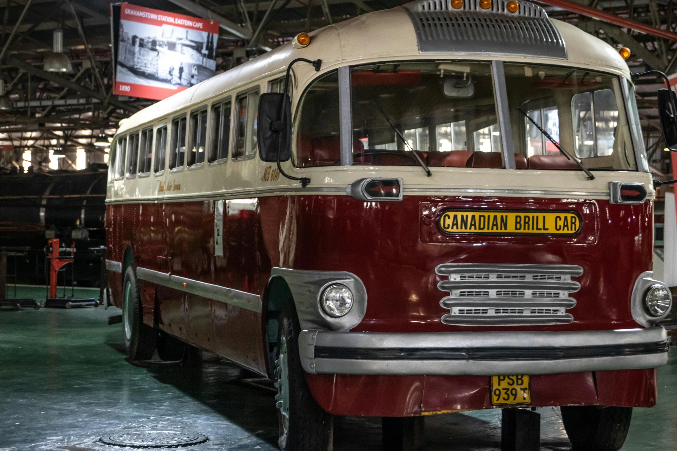 a red and white bus parked inside of a building, drumheller, displayed in the exhibition hall, montreal, nostalgic 8k