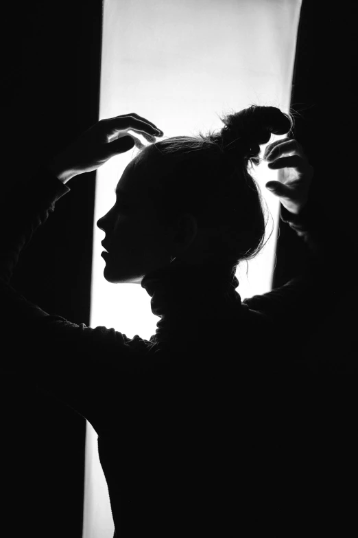a black and white photo of a woman combing her hair, by Alexis Grimou, anthropomorphic silhouette, topknot, difraction from back light, resembling a mix of grimes