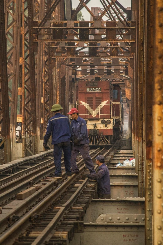 a couple of men standing on top of a train track, howrah bridge, repairing the other one, train in a tunnel, myanmar