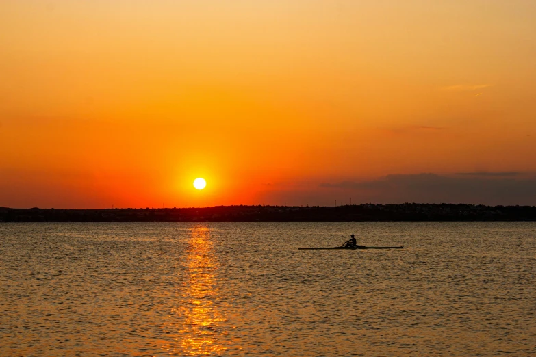 the sun is setting over a body of water, pexels contest winner, sculls, with a bright yellow aureola, ron cobb, over the horizon