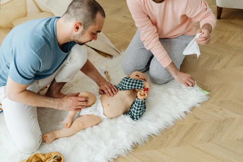 a man and a woman are playing with a baby, by Julia Pishtar, pexels contest winner, blue'snappy gifts'plush doll, injured, geometric, laying down