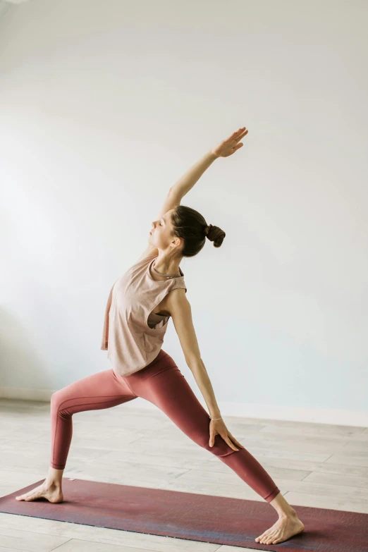 a woman doing a yoga pose while leaning on a mat