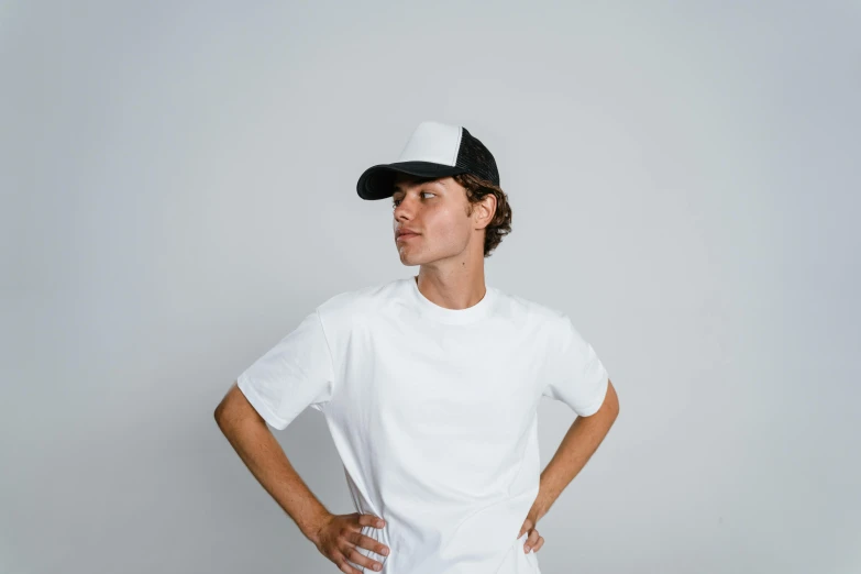 the boy is posing for a po wearing a white uniform and black baseball cap