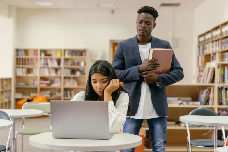 a man and woman looking at a laptop in a library, trending on pexels, standing in class, bullying, brown, standing upright