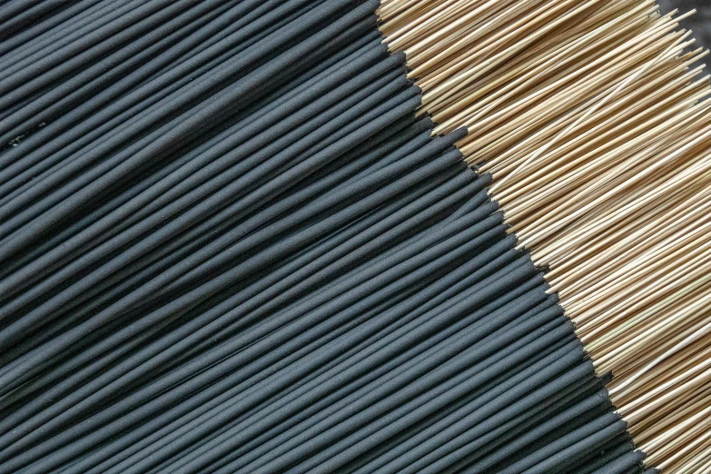 a pile of toothpicks sitting on top of a table, sōsaku hanga, carbon black and antique gold, zoomed in, incense, demur