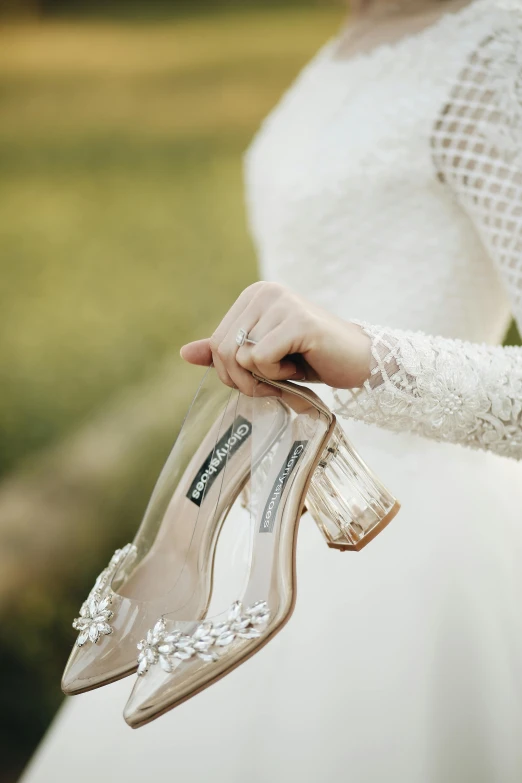 a woman holding onto a clear shoe with an elegant flower