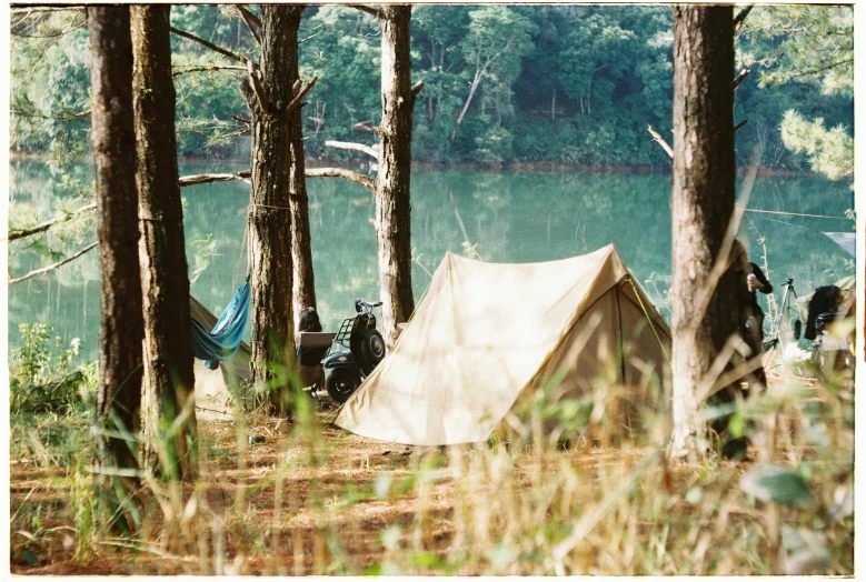 a tent in the woods next to a body of water, a polaroid photo, motorbike, laid - back, brown, fujicolor sample