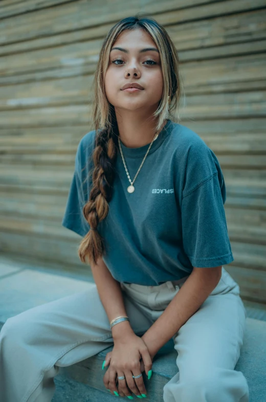 a woman sitting on a ledge in front of a wall, by Mark Arian, trending on pexels, in tshirt, portrait sophie mudd, ((greenish blue tones)), high detail portrait photo