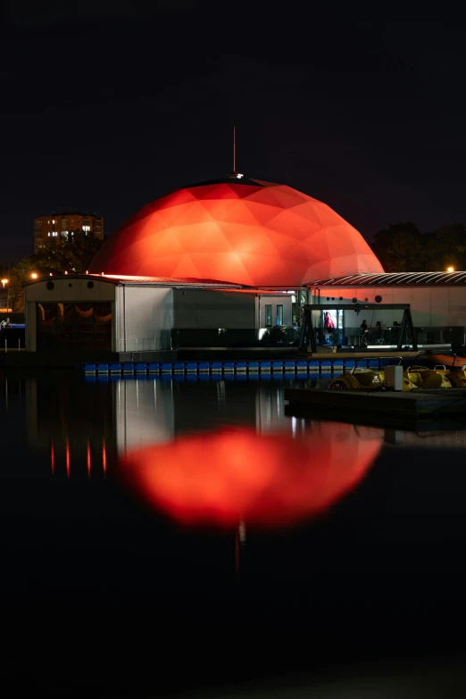 a large building in the dark by water with lights on