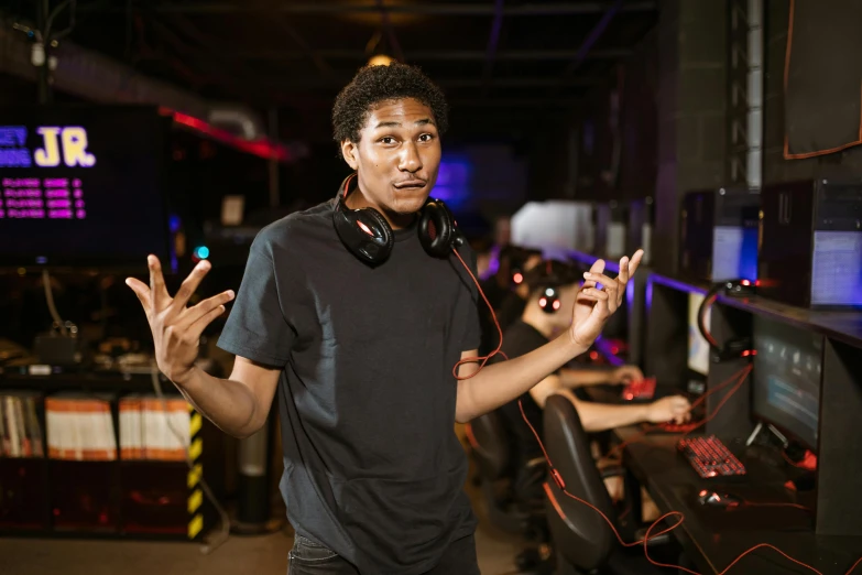 a man with headphones standing in front of a computer, arcade game, doing a sassy pose, mkbhd, high quality photo