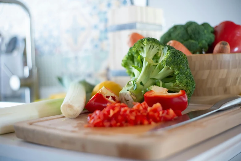 a wooden cutting board topped with vegetables on top of a counter, by Dan Content, background image, broccoli, eye - level medium - angle shot, extra crisp image