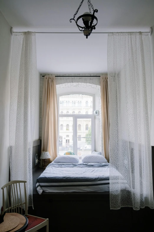 a bedroom with two windows and a bed that has a cover