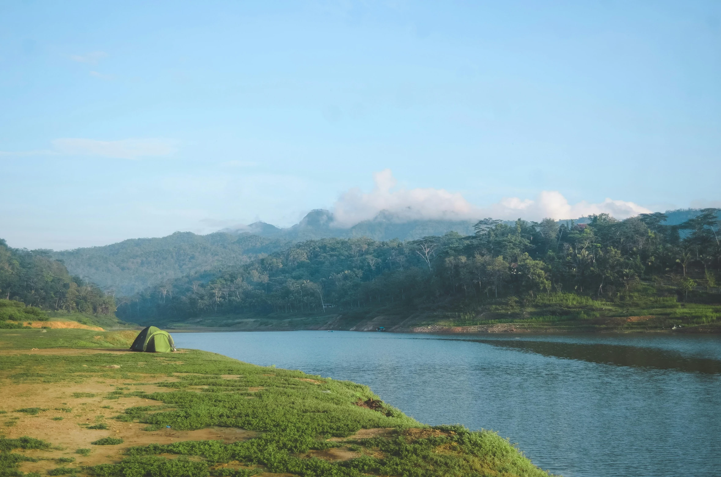 a tent pitched up next to a body of water, pexels contest winner, hurufiyya, sri lankan landscape, green hills, blue river in the middle, warm and calm