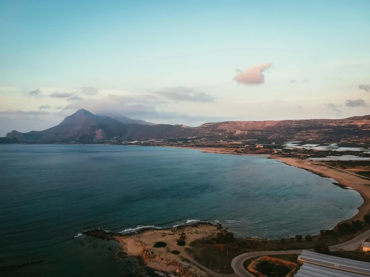 a road runs alongside the ocean and is next to some mountains