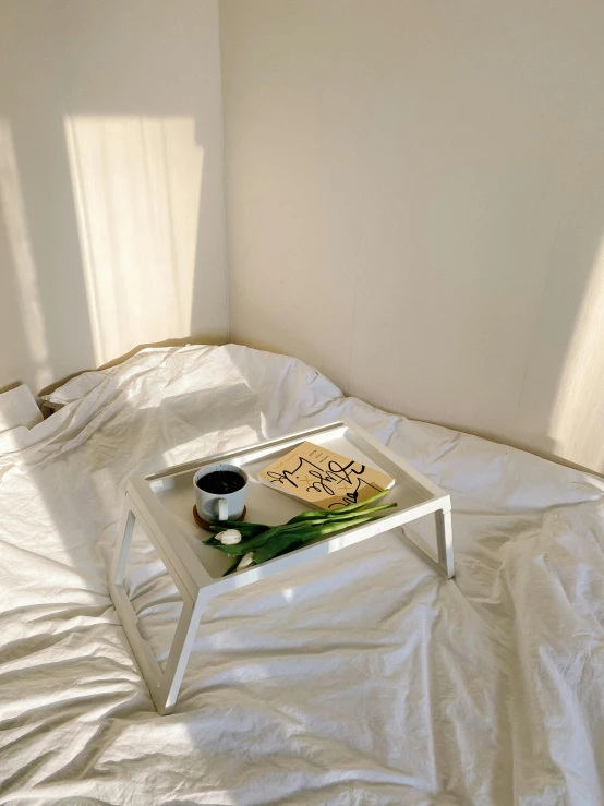 an empty bed with sun coming through and white sheets