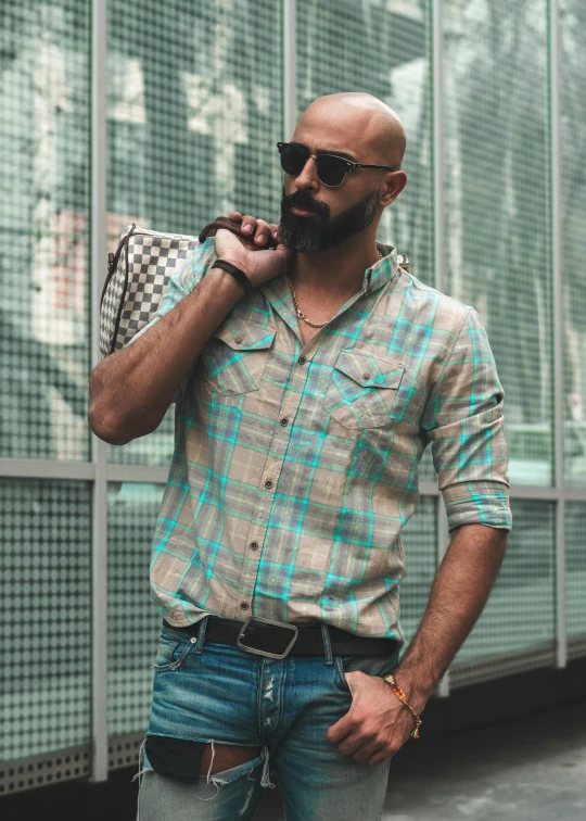 a bald man is standing near a building and holding a backpack