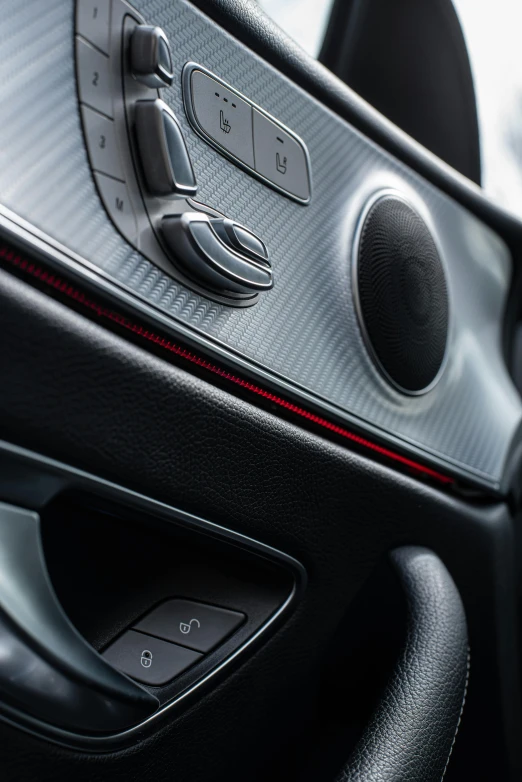 a close up of the interior of a car, soft grey and red natural light, shiny knobs, front left speaker, black car