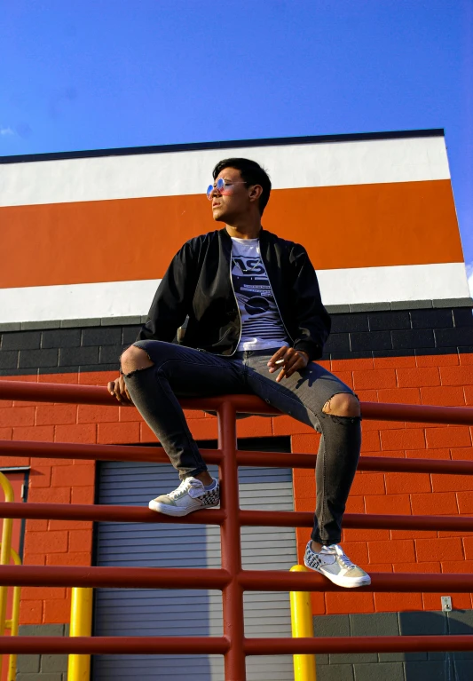 man sitting on rail and wearing sunglasses while looking up