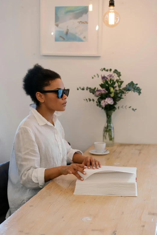 a woman sitting at a table reading a book, art & language, wearing shades, slightly minimal, ashteroth, non binary model