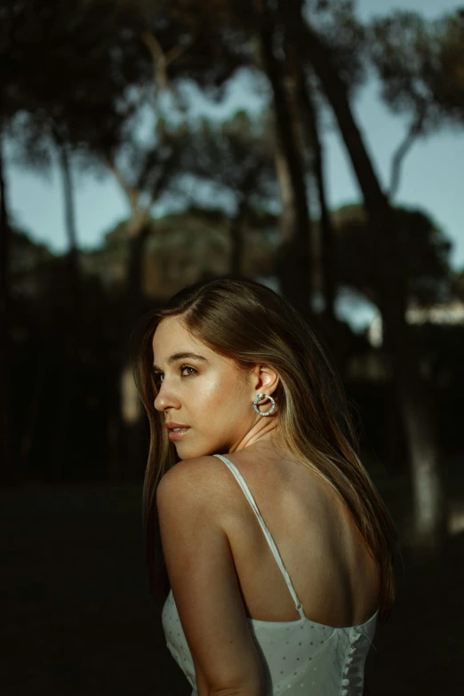 a woman in a white dress posing for a picture, inspired by Elsa Bleda, pexels contest winner, silver earring, summer evening, looking from shoulder, olivia culpo