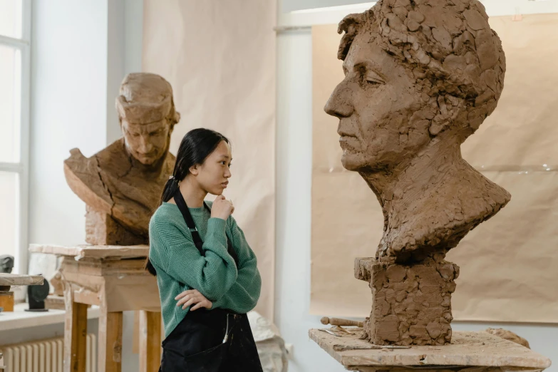 a woman standing next to a bust of a man, a marble sculpture, inspired by Fei Danxu, pexels contest winner, academic art, made of clay, giacometti, right side composition, large portrait