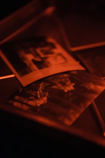 a book sitting on top of a table next to a candle, inspired by Nan Goldin, holography, detail shots, tintype photo, orange and red lighting, 4k photo”