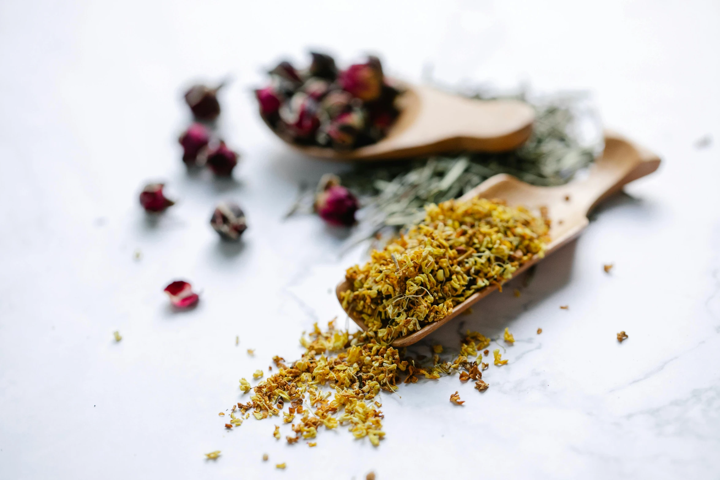 a wooden spoon filled with dried flowers next to a wooden spoon filled with dried flowers, by Matthias Stom, trending on unsplash, hurufiyya, yellow robe, food particles, on a white table, miniature product photo