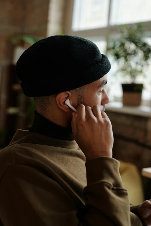 a man sitting at a table talking on a cell phone, trending on pexels, renaissance, airpods, close up shot from the side, sleek, headphones on