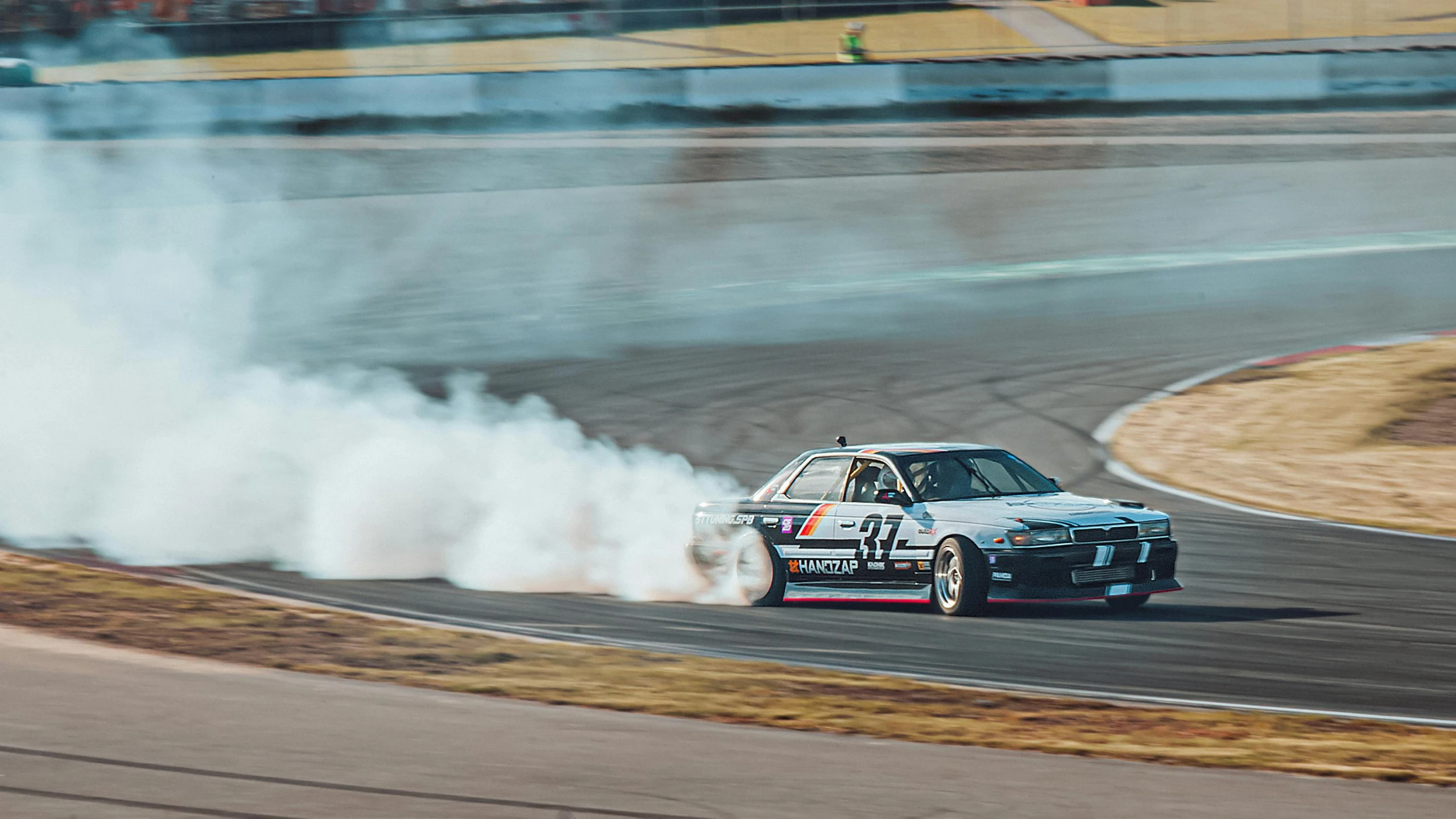 a car doing stunts while exploding smoke on the track