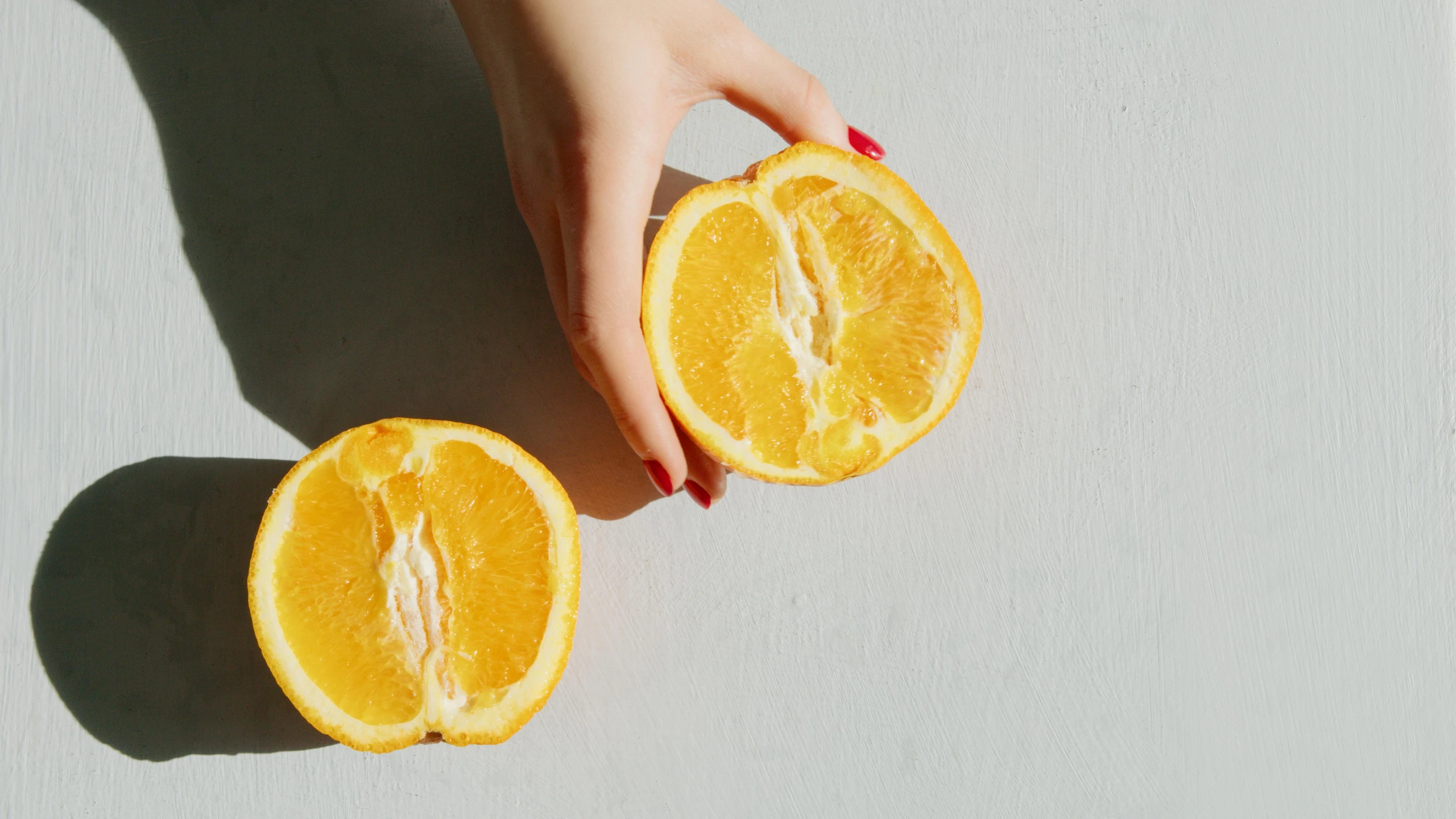 a woman's hand holding a half of an orange, trending on pexels, photorealism, background image, adult pair of twins, without text, lemonade