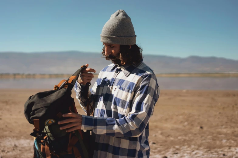 the man is holding a backpack and putting it into his pocket