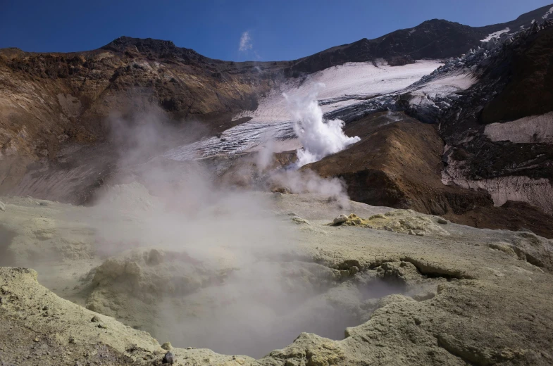 a small hole in the rocks with steam rising out