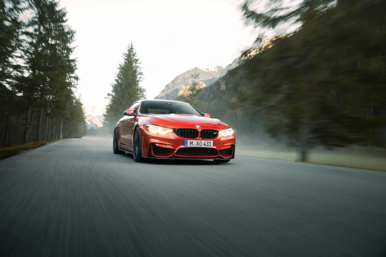 a red car driving down the road with trees in the background