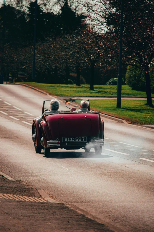 an old model red automobile driving down the road