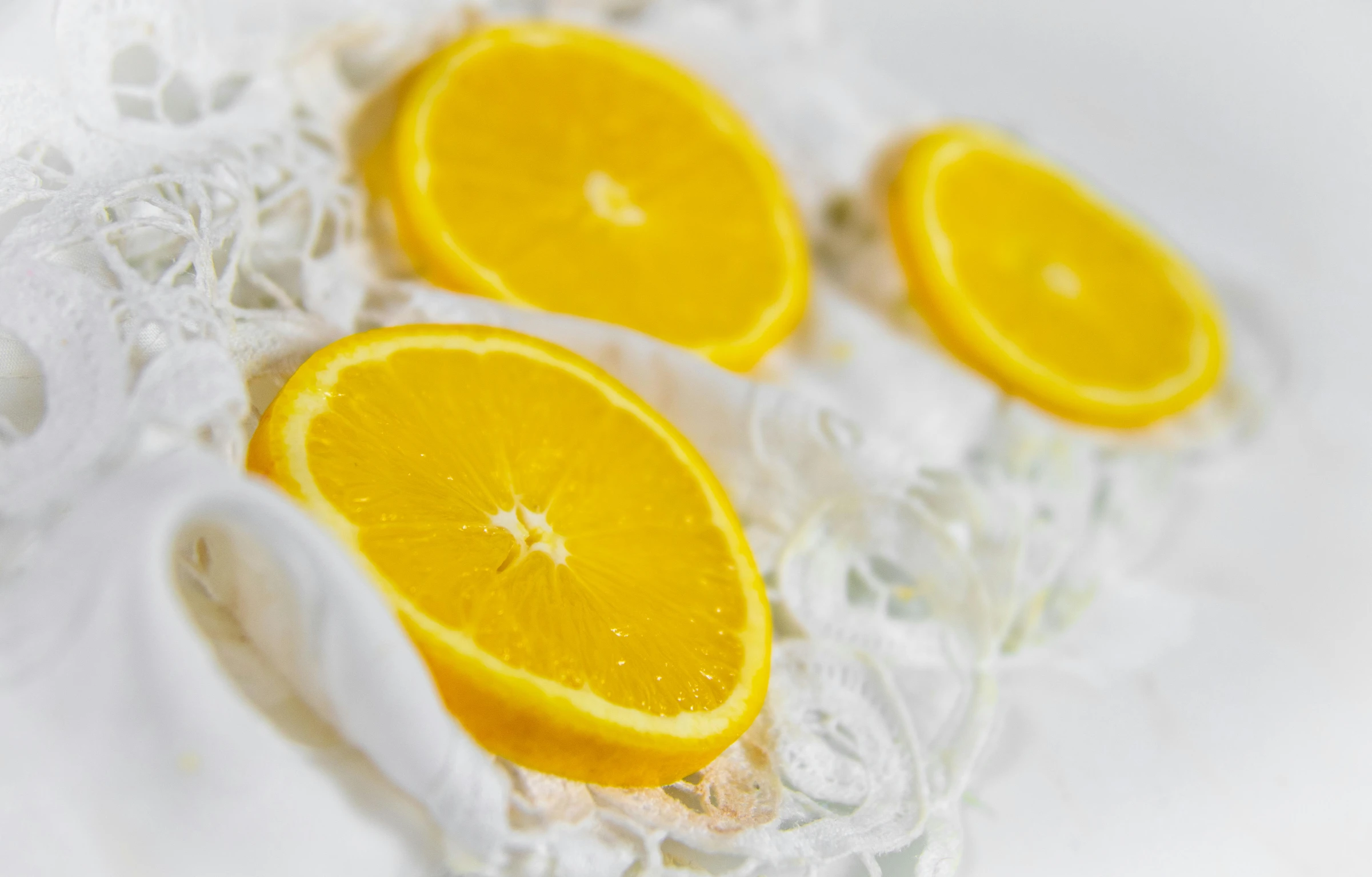 a bunch of orange slices sitting on top of a table, a portrait, inspired by Christo, pexels, subject made of white mesh rope, milk - bath effect, yellow translucent lace, closeup at the food