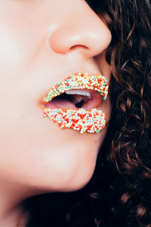 a close up of a woman with a donut on her mouth, inspired by Bert Stern, trending on pexels, pointillism, made of candy, lip scar, curls, multicolor