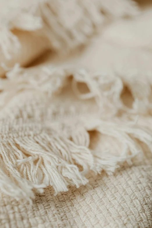 a close up of a blanket on a bed, inspired by Marià Fortuny, trending on unsplash, cotton fabric, vanilla, zoomed in, detailed product image