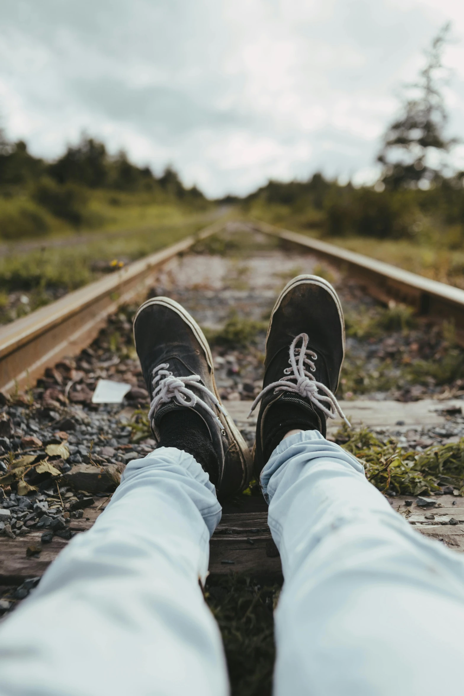 a person sitting on a train track with their feet up, trending on pexels, realism, countryside, distressed, teenage, canvas